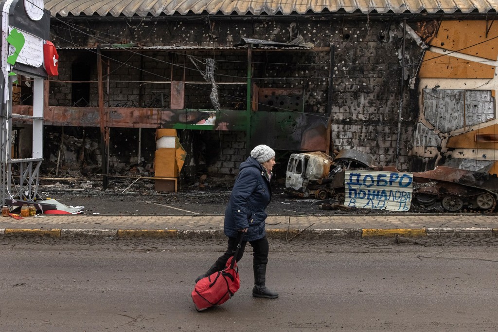 A woman carrying a suitcase coming from the town of Bucha walks past a destroyed building on the front line in the town of Irbin, Kyiv (Kyiv) region, Ukraine, March 04, 2022