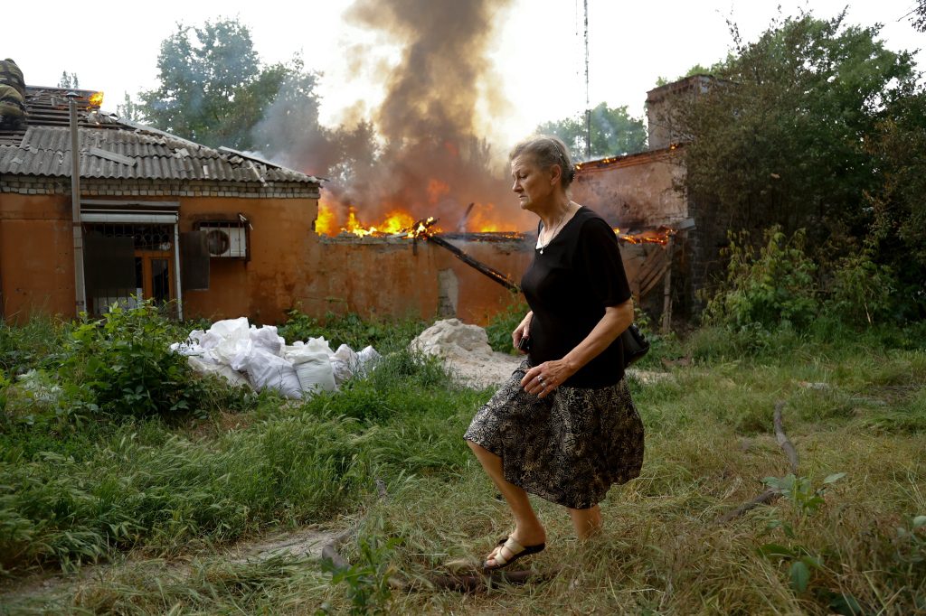 A woman escapes from a house that caught fire after a bombing in Donetsk.