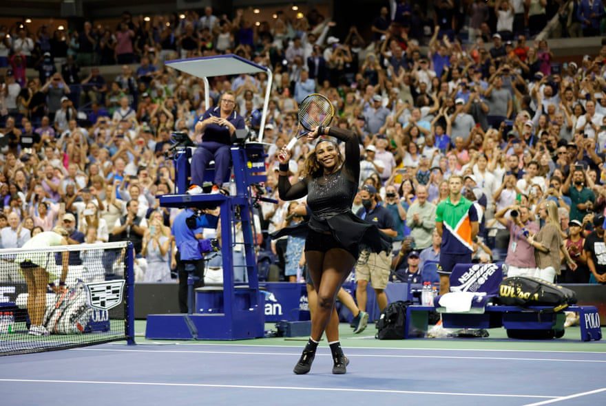 Serena Williams raises her racket and arm to the crowd as she stands on the court after her victory