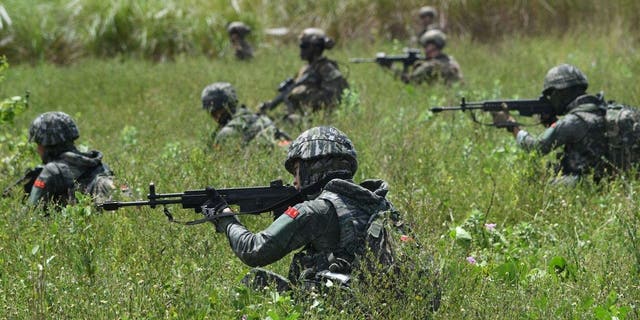 Marines from South Korea and the United States take up positions during a joint amphibious landing exercise with their Filipino counterparts on a beach facing the South China Sea in San Antonio, Zambales, October 7, 2022. 
