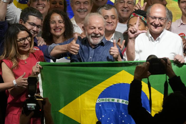 Louise in & # xe1;  cio Lula Da Silva, his wife Rosangela, and fellow Silva racer Geraldo Alckmin smile while carrying the Brazilian flag among a crowd of fans.